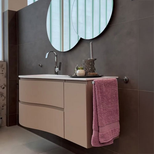 Der Waschtisch mit Unterschrank ist in mattem Hellbraun gehalten. Die runden Spiegel darüber unterstreichen die exklusive Optik.